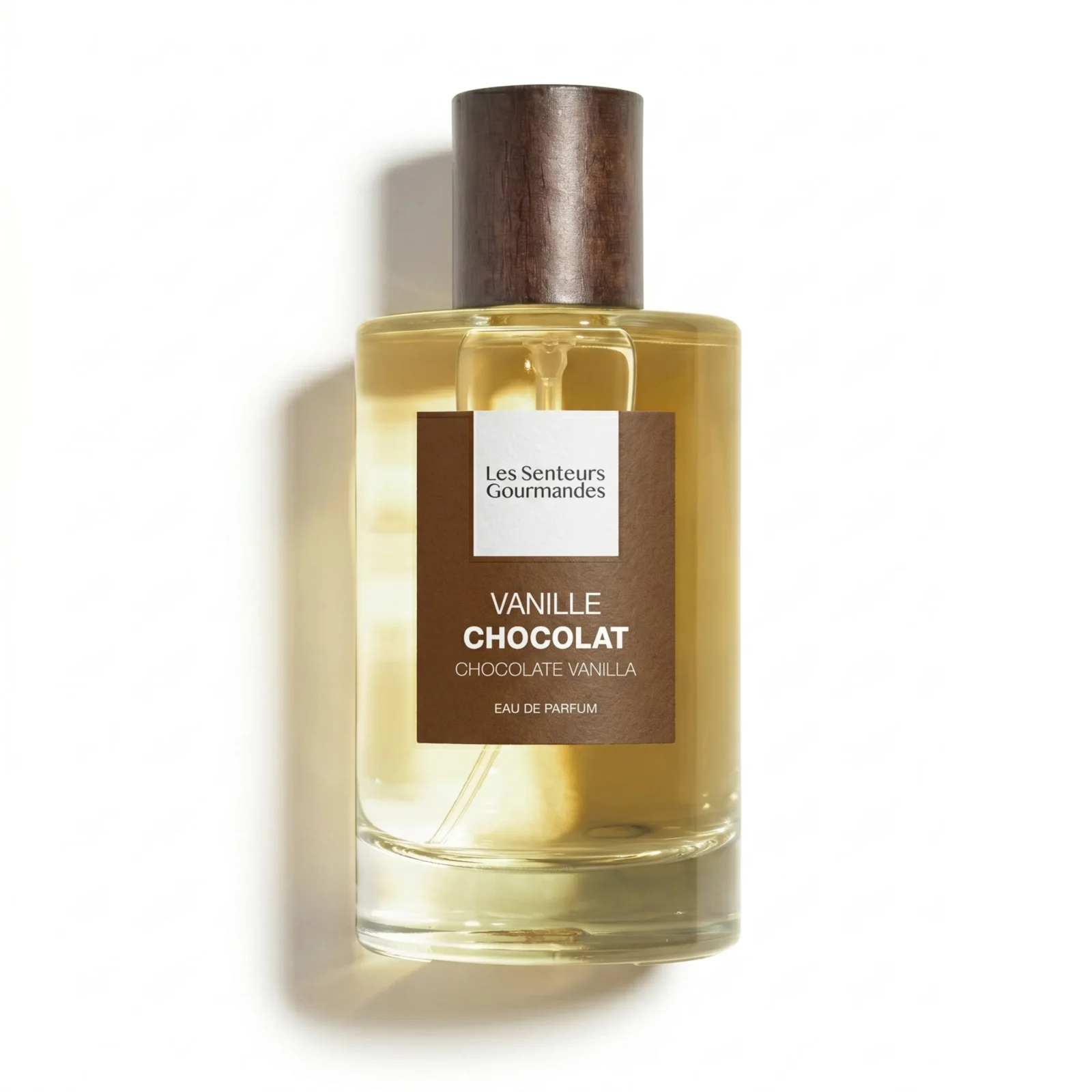 Grand flacon 100ml d'Eau de Parfum Vanille Chocolat de la marque Les Senteurs Gourmandes, bouteille en verre transparent mettant en valeur un jus doré clair, avec son bouchon cylindrique en bois foncé et une étiquette carrée marron chocolat texturée.