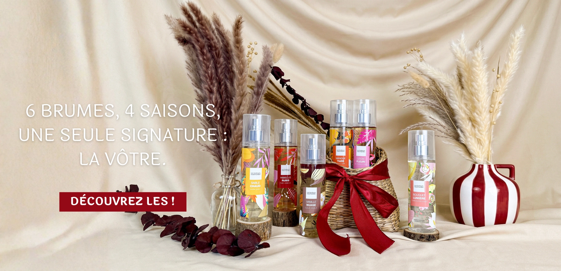 Six brumes parfumées sans alcool Les Senteurs Gourmandes disposées avec des fleurs séchées et un nœud en velours rouge, collection 4 saisons